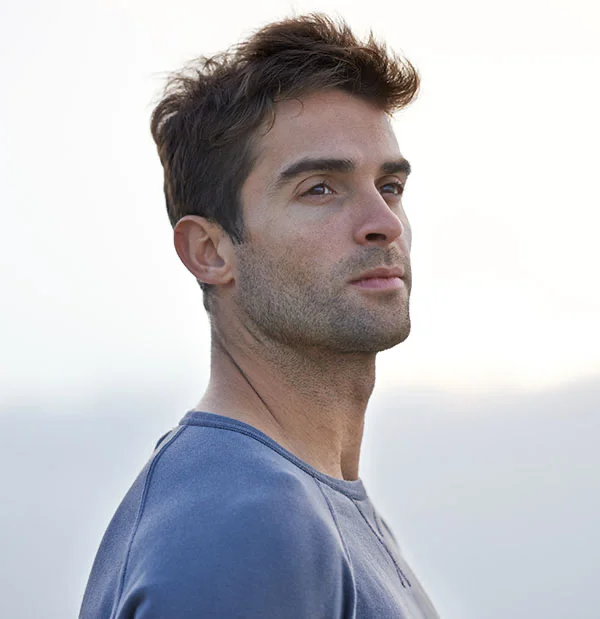 Confident man standing against a bright sky, dressed in a casual, modern outfit, looking off into the distance - Browlift in Portsmouth, NH
